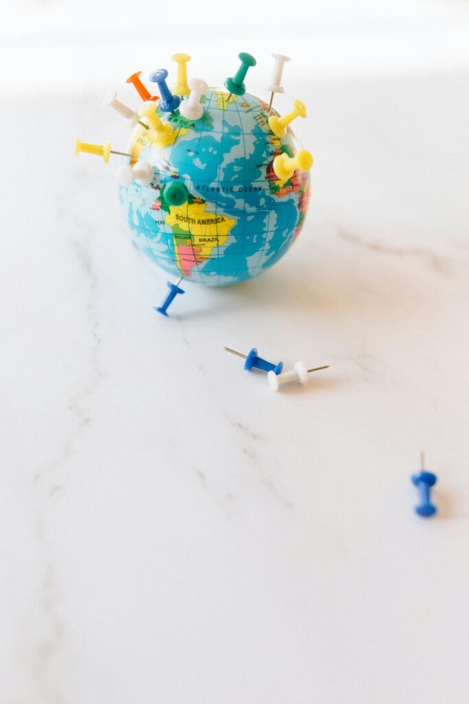 A small globe adorned with colorful pins, symbolizing travel and world exploration.